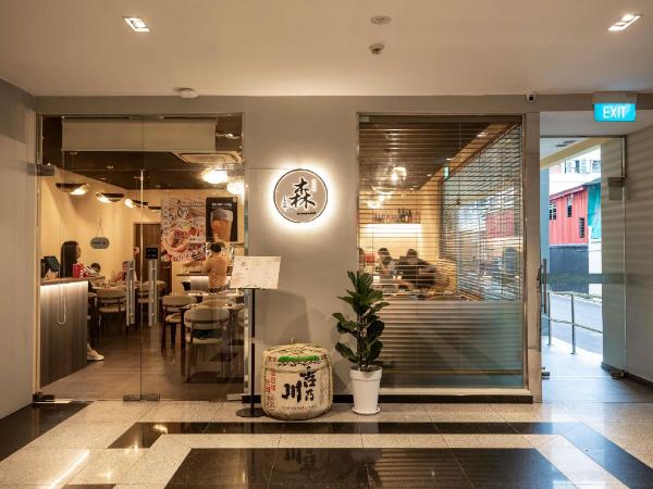 丸い看板と鉢植えのあるSen Restaurantの入口