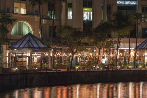 夜の川沿いの低層棟と屋外席の照明