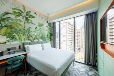 植物柄の壁と大きなベッド、壁付けテレビのDeluxe Room