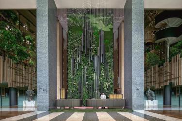 植物が連なる吹き抜けと大理石調の通路
