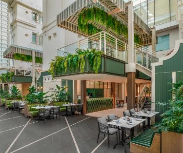 吹き抜けと植物、テーブルのある飲食スペース