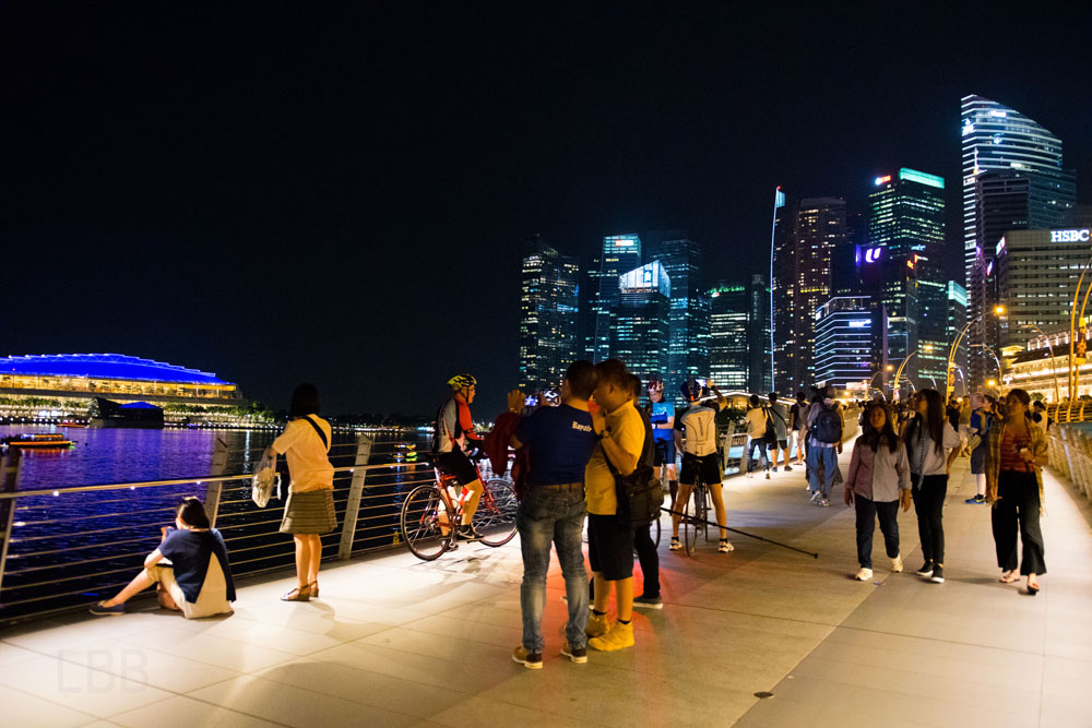 座り込んで夜の写真撮影を楽しむシンガポール観光客